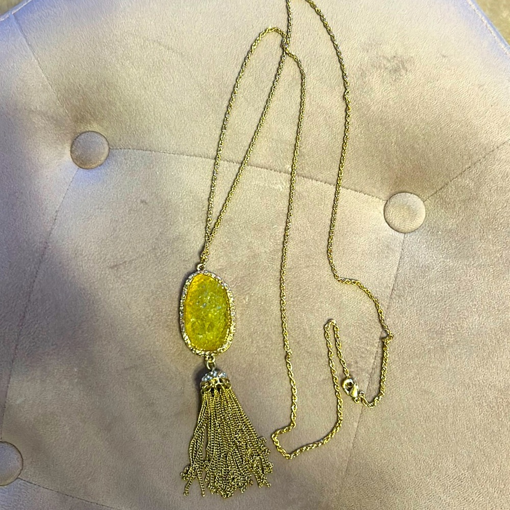 Long chain gold necklace with textured crystal like yellow  stone.